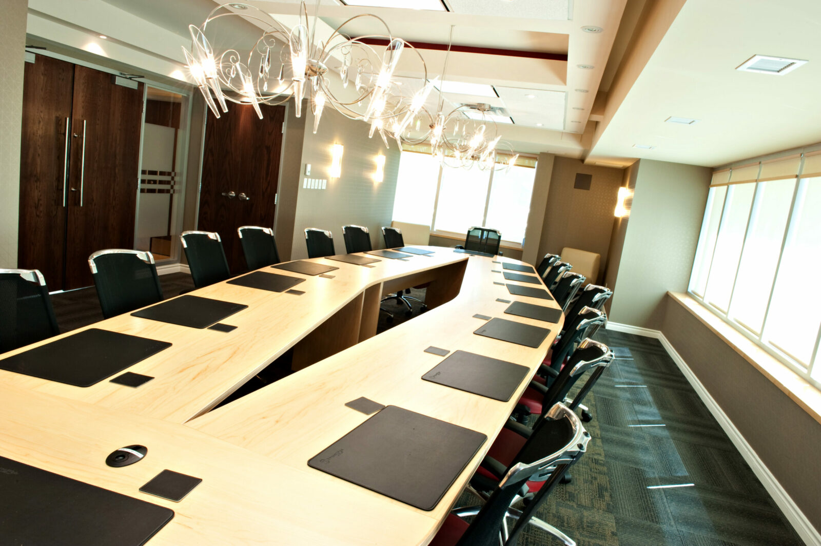 Our Hamilton, Ontario law firm features a contemporary conference room equipped with an elongated table, sophisticated black chairs, and exquisite chandeliers.