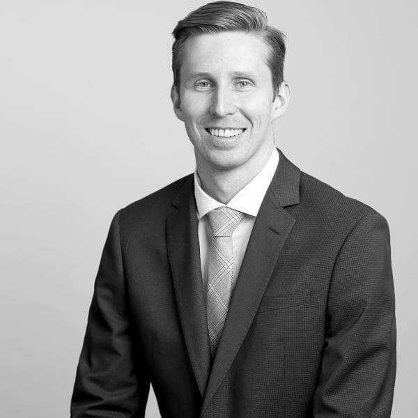 A professional black-and-white portrait of a gentleman, donning a business suit and tie, displays his welcoming smile for our esteemed Law Firm based in Hamilton, Ontario.