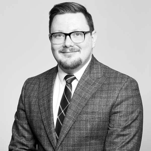 Esteemed legal professional, donning suit and tie with spectacles, gracing a professional portrait at a Law Firm located in Hamilton, Ontario.