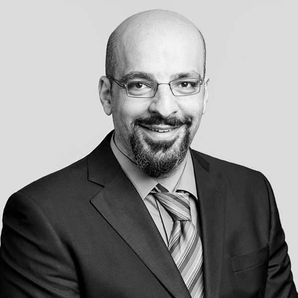 Accomplished professional adorned in a suit and striped tie, offering a pleasant smile towards the camera, depicted in a dignified black and white portrait for our prestigious law firm located in Hamilton, Ontario.