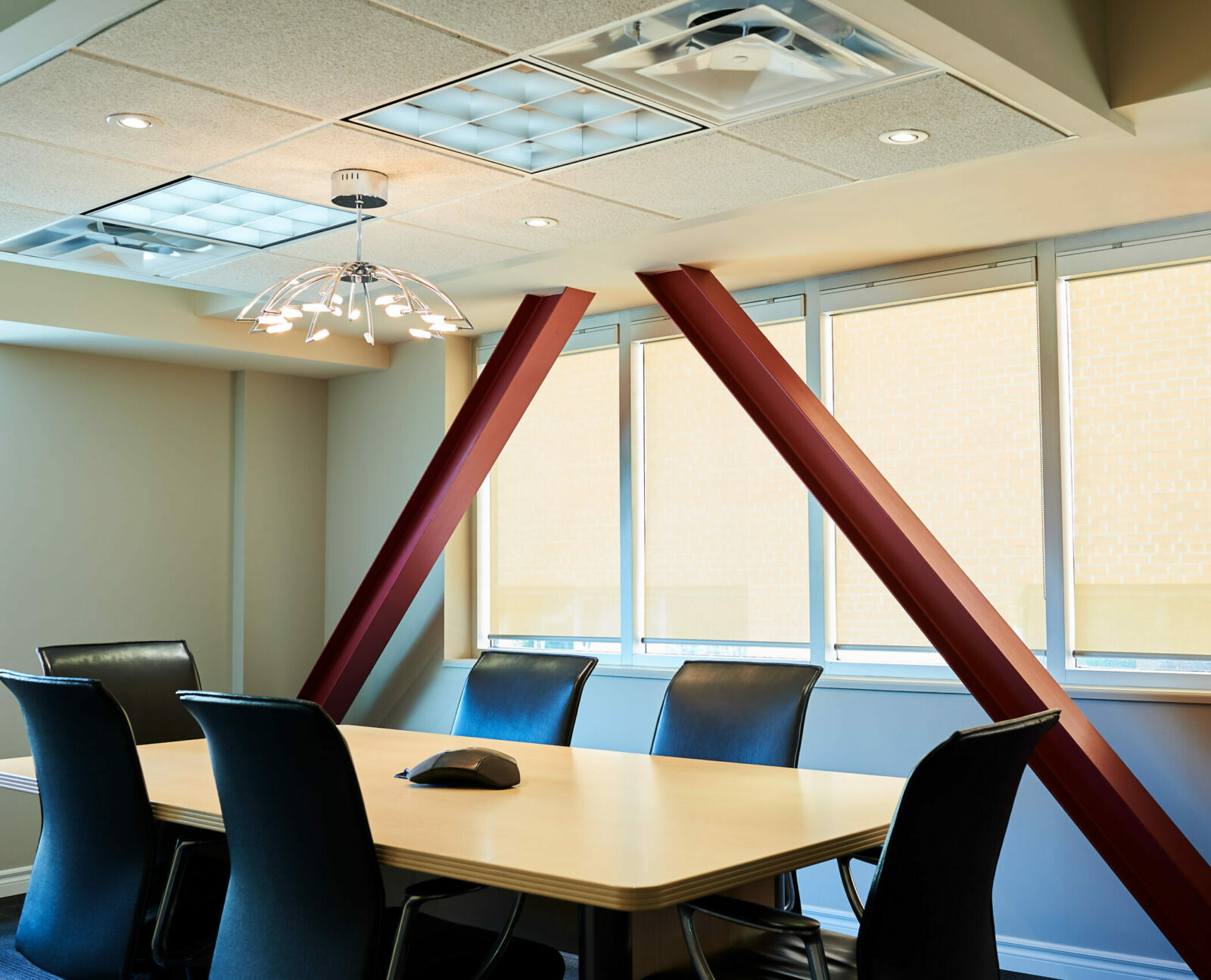 Our law firm in Hamilton, Ontario boasts a contemporary conference room outfitted with a polished wooden table, sleek black chairs, and expansive windows shaded by blinds.