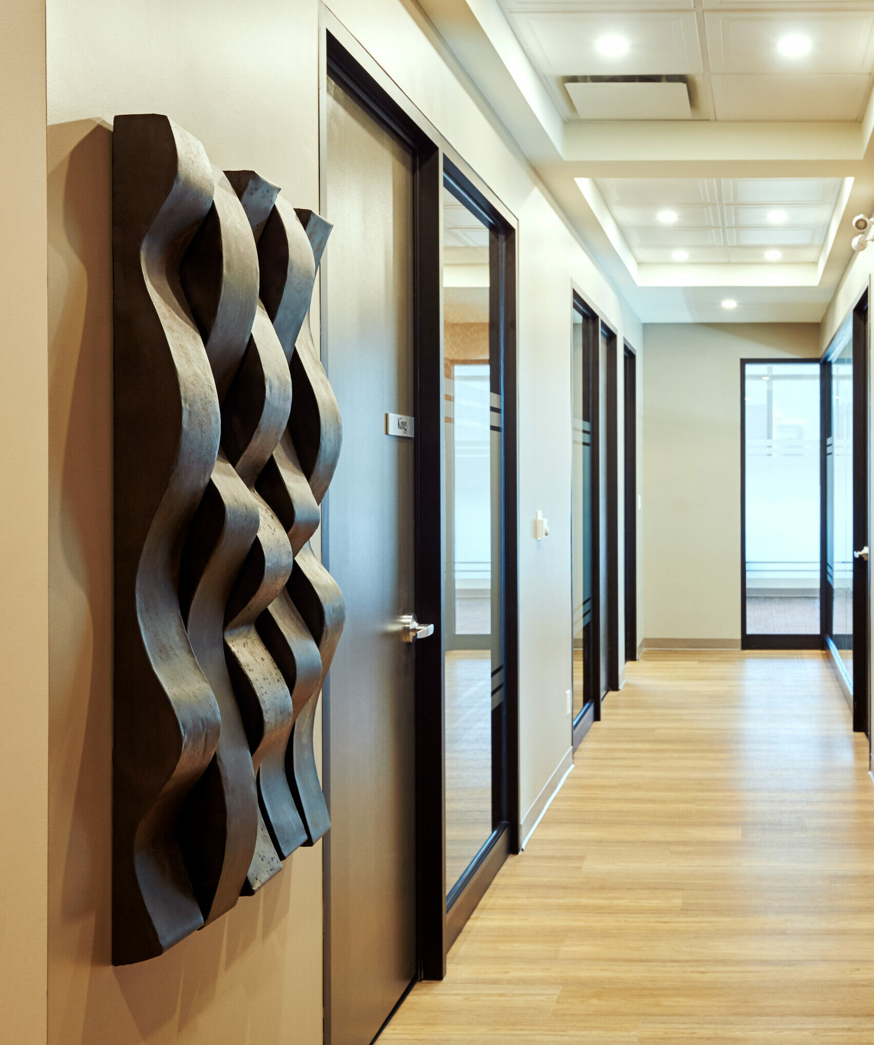 Our law firm, located in Hamilton, Ontario, showcases a contemporary hallway adorned with an artistic wall sculpture and multiple office entrances.