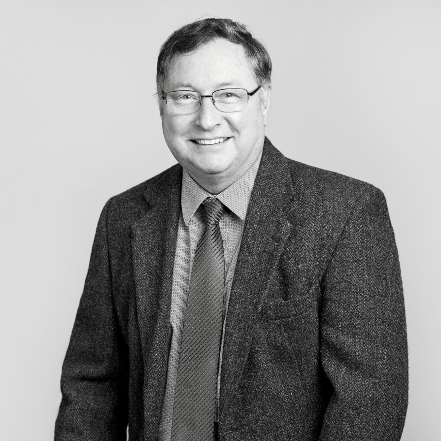 A professional individual, dressed in formal business attire and displaying a subtle smile, is captured in a sophisticated black and white photograph at our reputable law firm in Hamilton, Ontario.